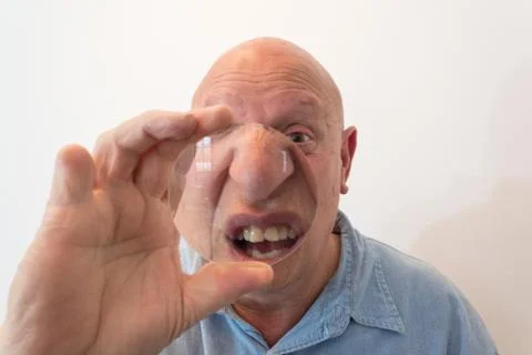 Older man looking through a large lens over nose and mouth, distortion, bald Foto stock