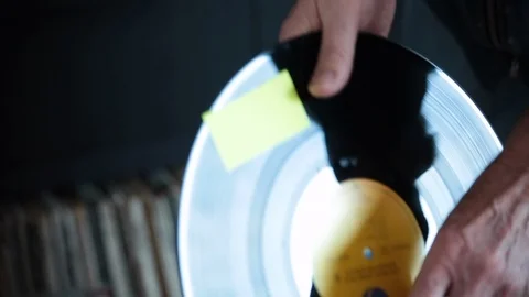 Older man packs LP back into its sleeve in his living room Stock Footage 98740375