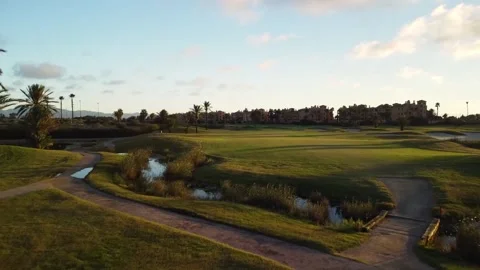Older man playing golf. He takes a swing. Drone view following the ball thr.. Stock Footage 252603857