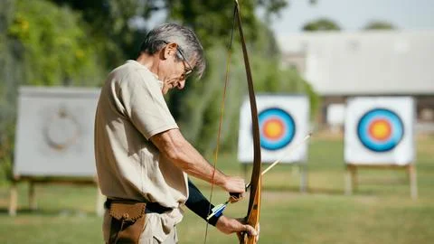 Older man practicing archery aiming for targets Stock Photos
