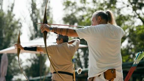 Older man practicing archery, aiming at a goal Stock Photos