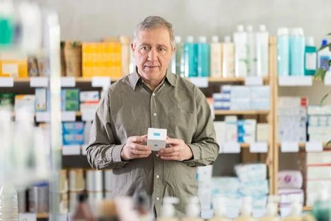 Older man reading label on box of medicine in drugstore Stock Photos