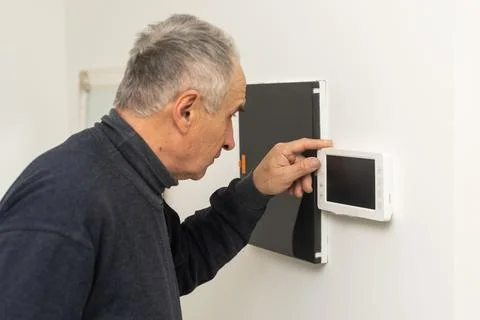 Older man repairing intercom system Stock Photos