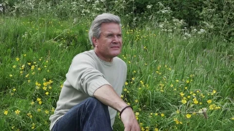 Older man sat in meadow looking into distance Stock Footage 76299595