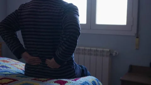 Older man sitting alone on bed suffering from back pain 스톡 동영상 332048905