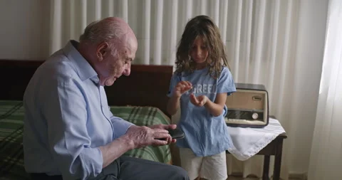 Older man sitting on bed next to his grandson Stock Footage 272943577