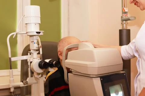 An older man taking an eye test examination at an opticians clinic.Optometry Stock Photos
