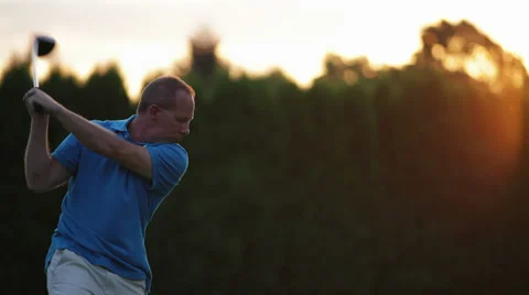 An older man tees off in to the sunset while playing golf Stock Footage 33868862