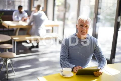 Older Man Using Digital Tablet In Cafe