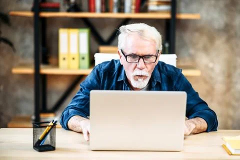Older man is using laptop for working indoor Stock Photos
