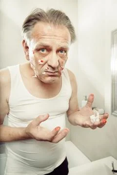 Older man using a razor to shave himself cut himself and bleed Stock Photos