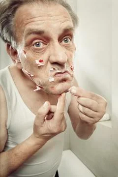 Older man using a razor to shave himself cut himself and bleed Stock Photos