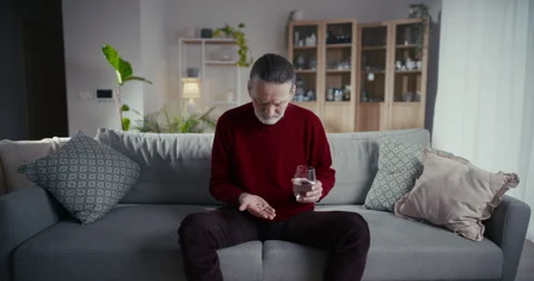 Older man using smartphone on sofa in bright living room Vídeo Stock 336281159