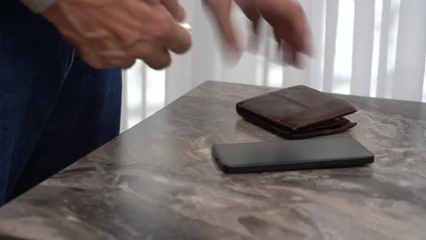 The older man's hands picked up pocket essentials from the table: keys, wallet Stock Footage 304774207