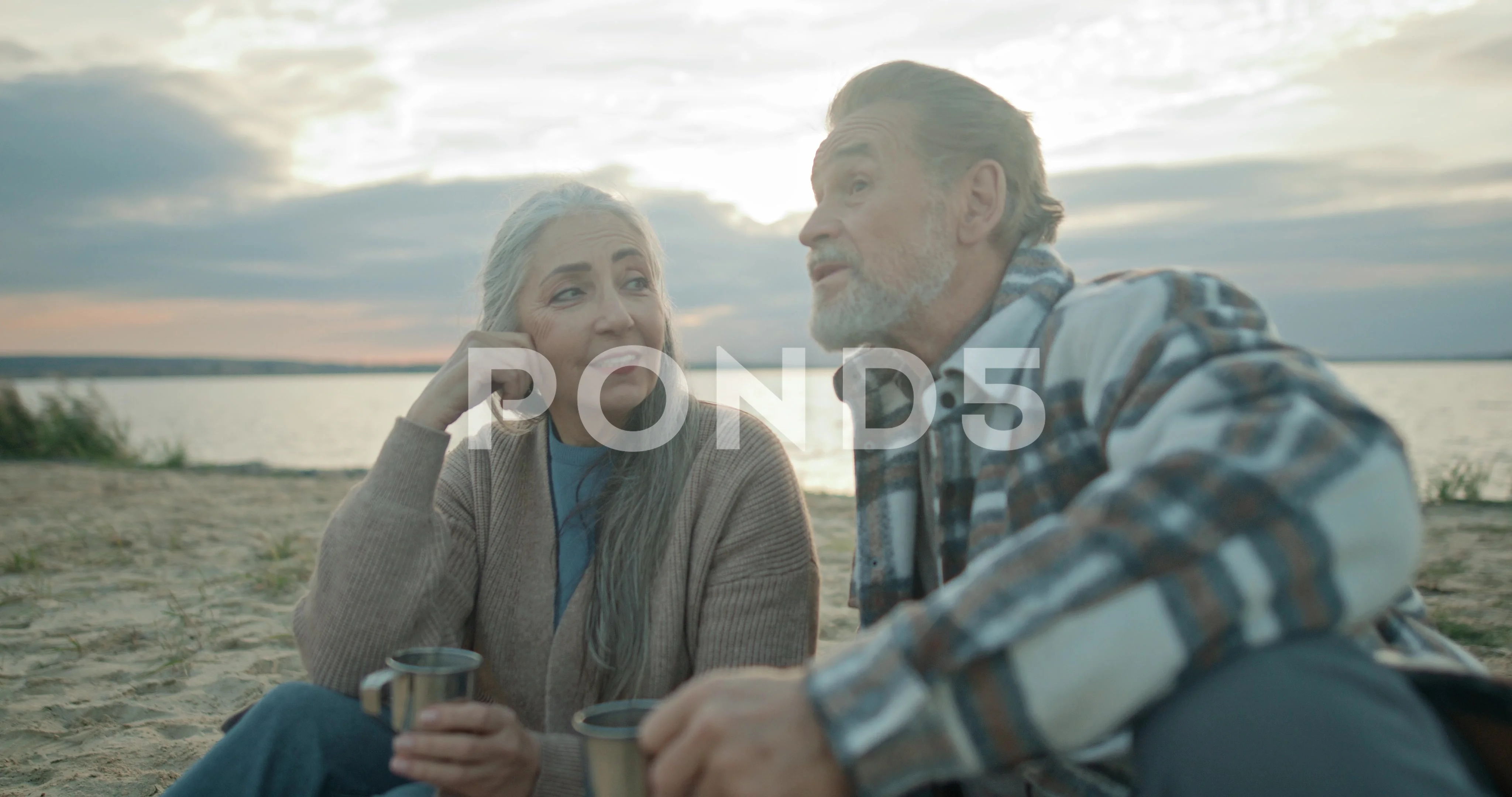 Older married couple having relax near pond. Mature couple cheerfully