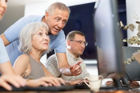 Older mentor explaining something to elderly woman during computer class Fotos de archivo