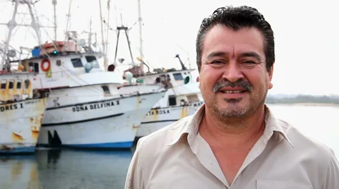 A older Mexican man poses for the camera down by the fishing docks Stock Footage 34021437