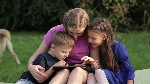 Older sister with children using a tablet and having fun in the yard Stock Footage 80895898