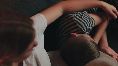 Older sister comforts her younger brother as he sleeps on her lap on a comf.. Stock Footage 304450100