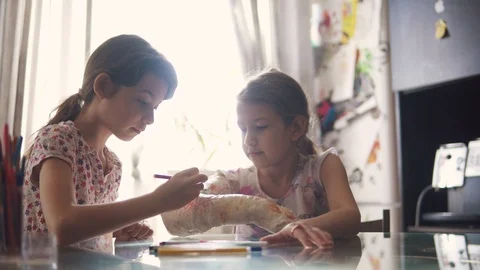 Older sister paints a plastered hand to her younger sister. child cares and Stock Footage 123713288