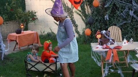 Older sister pulling siblings in a wagon during Halloween party Stock Footage 317773854
