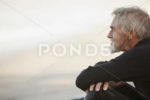 Older Surfer Sitting On Beach