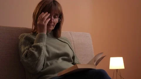 Older Woman Sitting On An Armchair And Reading A Book Stock Footage