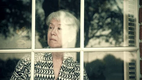 Older woman standing next to a window happy to see someone 4k Stock Footage