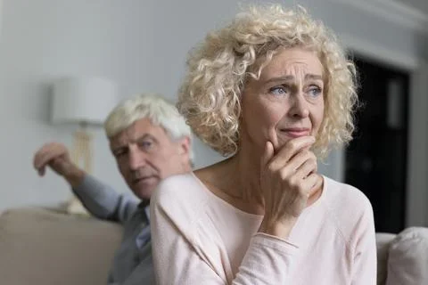 Older woman suffers from resentment after quarrel with angry husband Stock Photos