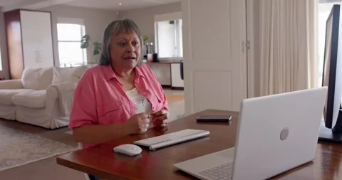 Older woman using computer and pointing at screen at home office desk Stock Footage 345886410