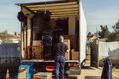 Older worker loading cardboard boxes onto moving truck Stock Photos