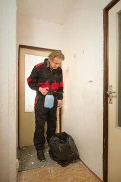 Older worker moisturing old wallpapers with water sprayer Stock Photos