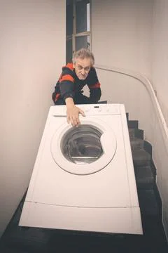 Older worker trasporting wash machine appliace with cart by stairs Stock Photos