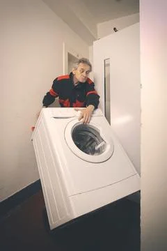 Older worker trasporting wash machine appliace with cart to elevator Stock Photos