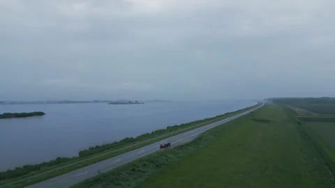 Oldtimer Car Driving Along a Dike Road by the Water Video stock 306380019