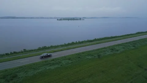 Oldtimer car Driving on Dike Beside Water Video stock 310597221