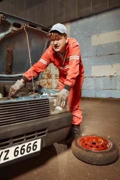 Oldtimer car enthusiast in overall checking car engine Fotos de archivo