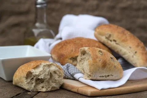 Olive bread rollis in rustic kitchen setting with utensils Stock-Fotos