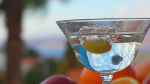 Olive falls into a glass with martini on a background of citrus fruits Stock Footage 113914938