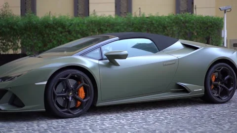 Olive Lamborghini stands on a pavement outside a hotel in Dubai Stock Footage 218593288