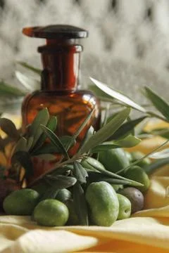 An Olive Oil Bottle Elegantly Surrounded by Fresh Olives and Vibrant Green .. Stock Photos