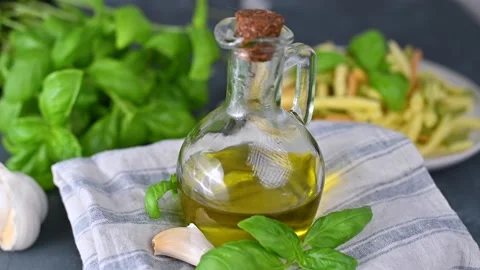 Olive oil in a bottle on the table, with fresh basil leaves, garlic. Ingredients Stock Footage 134042786