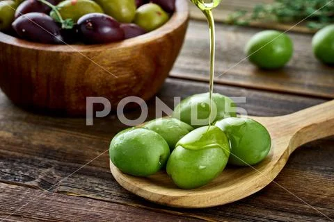 Olive oil pouring on big green olives Stock Photos