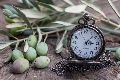 Olive time: olives with olive tree branch and pocket watch on old wood Stock Photos
