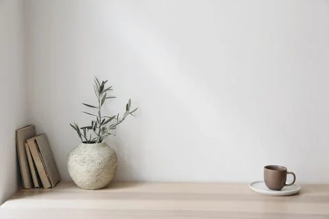Olive tree branches in beige textured vase. Brown cup of coffee, tea and old Foto stock