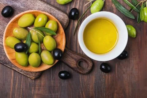 Olives and extra virgin olive oil in a bowl on wooden table Stock Photos