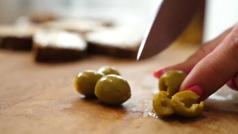 Olives are cut in half with a knife. Preparation of vegetable dishes. Stock Footage 282695799