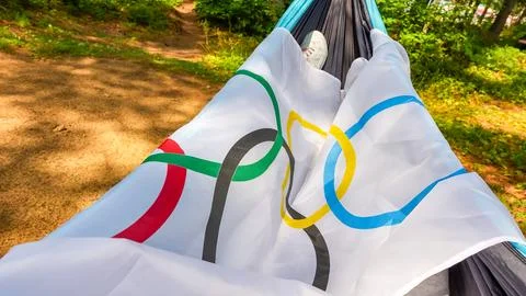 Olympic flag displayed in a hammock surrounded by greenery, showcasing the Stock Photos