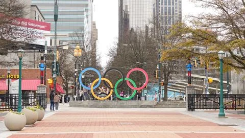 Olympic rings monument in Centennial Olympic Park with urban skyline and Stock Photos