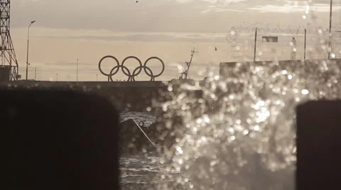 Olympic symbol on background. Splash of waves on the pier against the sun.  Video stock 51929590